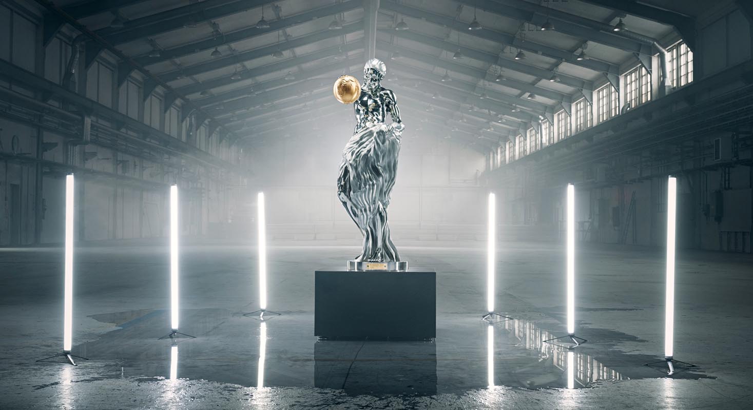A steel statue of a woman in a large room. The statue is holding a gold-colored globe in one of her hands.